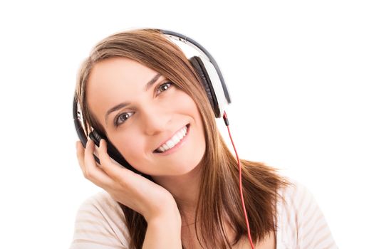 A portrait of a smiling young girl with headphones listening to music, isolated on white background.