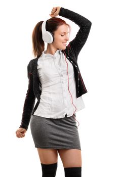 Beautiful student girl in school uniform with headphones, listening to music and dancing, isolated on white background.