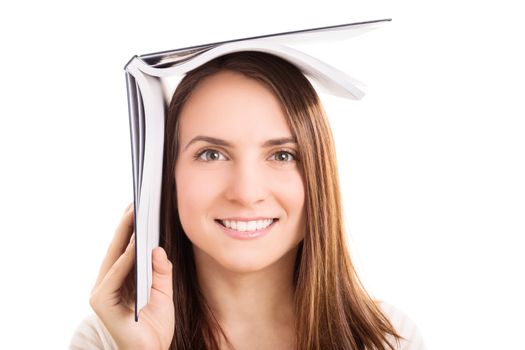 Young girl holding a book on top of her head, isolated on white background. I'm hiding from the exams.