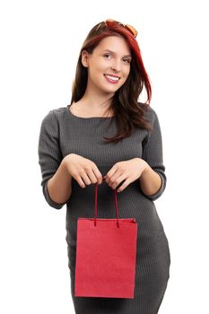 A portrait of a beautiful smiling young girl in a dress, holding a shopping bag, isolated on white background.