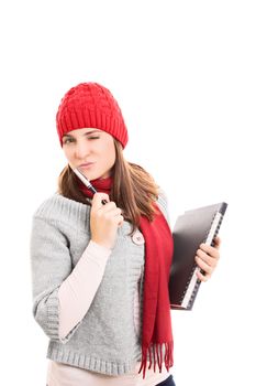 Portrait of a beautiful young woman winking, holding a pen, book and a notebook, wearing winter clothes. isolated on white background.