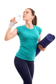 Portrait of a beautiful young girl holding an exercise mat and drinking water from a bottle, isolated on white background.