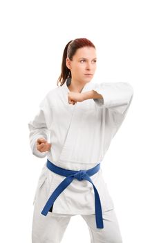 A portrait of a young girl in a kimono with blue belt demonstrating a blocking technique, isolated on white background.