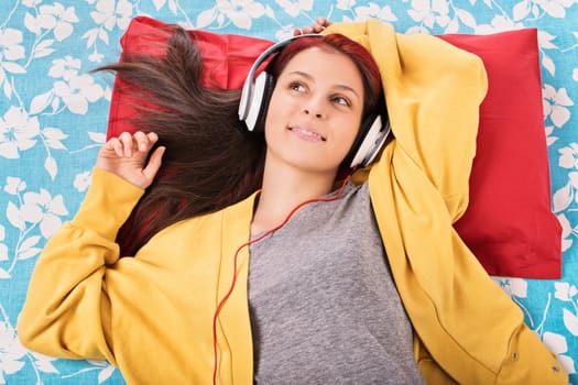My dream song. Beautiful young girl lying in bed, listening to music.