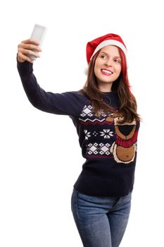 Young beautiful girl wearing a christmas hat taking a selfie, isolated on white background.