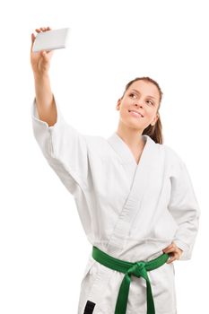 Sports and selfies. Smiling young girl wearing kimono taking selfie, isolated on white background.