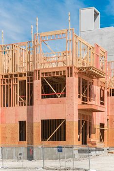Close-up of multistory condominium under construction with wooden lumber timber framework and concrete elevator shaft. Modern apartment complex rental living space construction area near Dallas, Texas