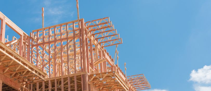 Panorama view low angle view of modern condominium building with large patio under construction near North Dallas, Texas. Wooden house with timber framing, truss, joist, beam close-up cloud blue sky