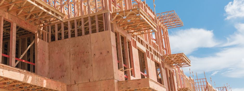 Panorama view low angle view of modern condominium building with large patio under construction near North Dallas, Texas. Wooden house with timber framing, truss, joist, beam close-up cloud blue sky