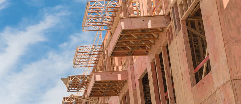 Panorama view low angle view of modern condominium building with large patio under construction near North Dallas, Texas. Wooden house with timber framing, truss, joist, beam close-up cloud blue sky