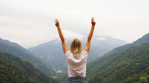 Cheering woman hiker open arms at mountain peak - nature and lifestyle