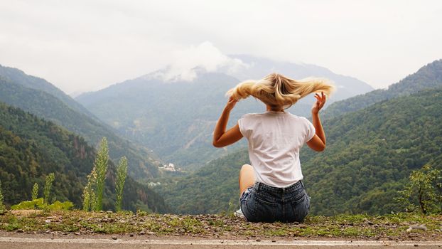 Cheering woman hiker open arms at mountain peak - nature and lifestyle