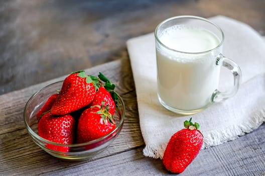 Fresh strawberries and milkshake on a wooden on wooden boards.