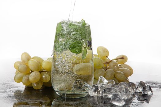 Glass of water, mint and grape on a glass background