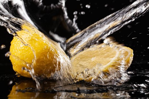 Lemon and pouring water on a black glass background