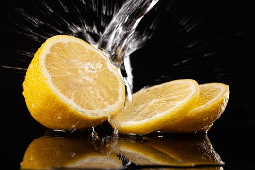 Lemon and pouring water on a black glass background