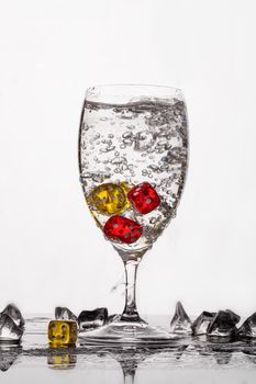 Dices, crystals of ice and glass of water ona glass backround