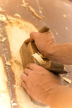 Closeup of woodworker's hands shaving with a plane in a joinery workshop