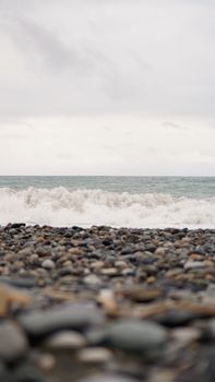 Pebble stones on the shore close up in the blurry light in the distance background.