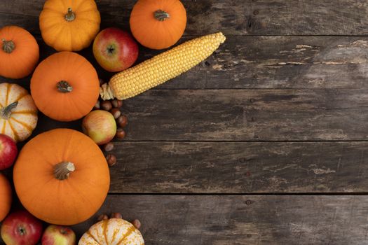 Autumn harvest still life with pumpkins, apples, hazelnut, corn, on wooden background, top view with copy space