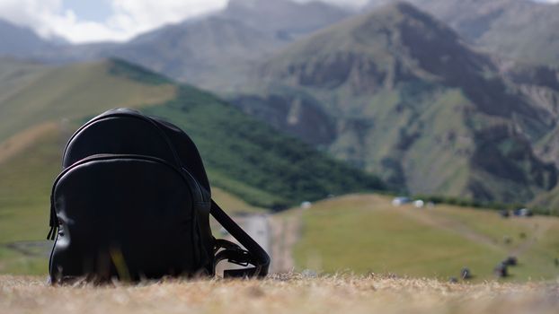 Black backpack on the background of Mount Kazbegi. Traveling in Georgia - Summertime