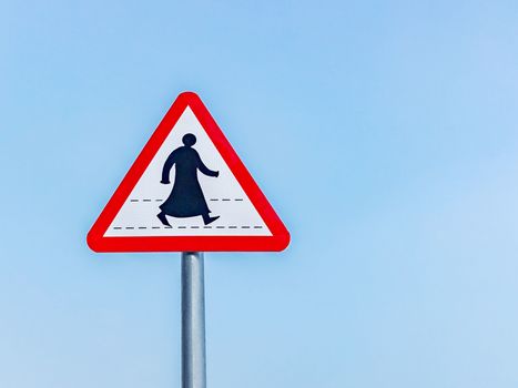 Sign prohibiting traffic for pedestrians in a southern Arab country, a silhouette of a pedestrian in traditional clothes, against a blue sky.