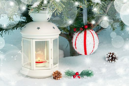 Christmas composition - a lantern with a burning candle and decorations under the Christmas tree.