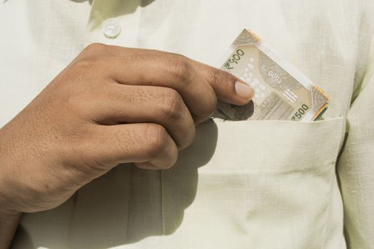 Man hand takes a indian currency out of his pocket close up