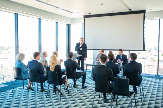 Business speaker with microphone in front of audience, conference, seminar concept