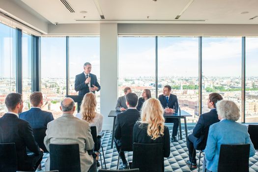 Business speaker with microphone in front of audience, conference, seminar concept
