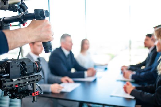 Videographer filming group of people at business meeting