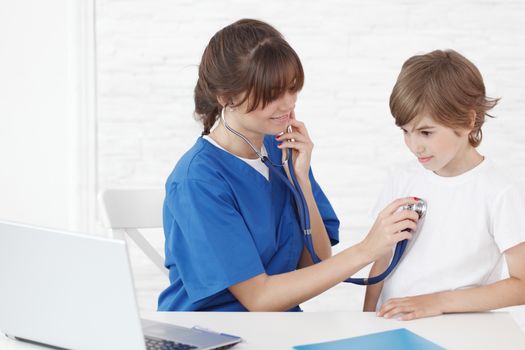 Female doctor listening to heartbeat of a boy, isolated on white