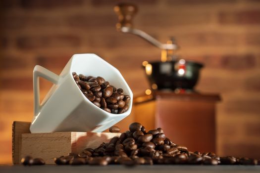 Coffee bean in the white cup and coffee grinder on wooden table. Concept breakfast or coffee time in morning.