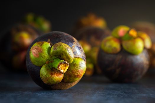 Mangosteen on black cement floor and morning light. Is a seasonal fruit in Thailand. Closeup and copy space for text.