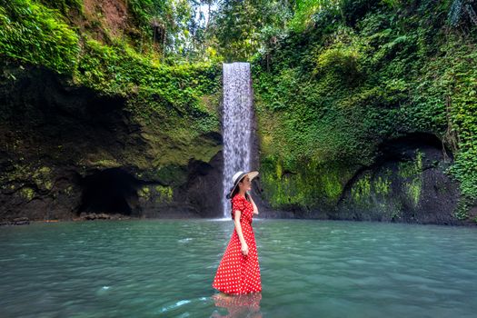 Beautiful girl standing in Tibumana waterfall in Bali, Indonesia.