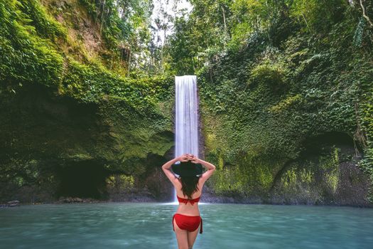 Woman standing in Tibumana waterfall in Bali island, Indonesia. Vintage tone