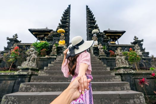 Women tourists holding man's hand and leading him to Besakih temple in Bali, Indonesia.