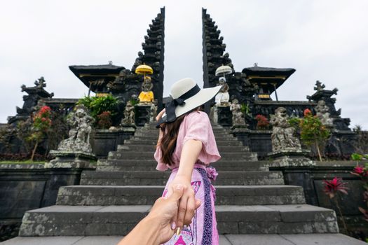 Women tourists holding man's hand and leading him to Besakih temple in Bali, Indonesia.