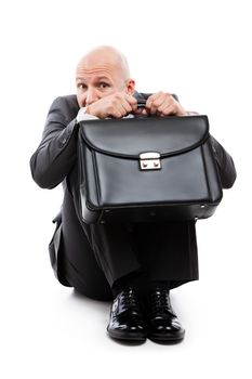 Business problems and failure at work concept - unhappy scared or terrified businessman in depression with fear and stress face expression hand holding briefcase sitting down floor white isolated