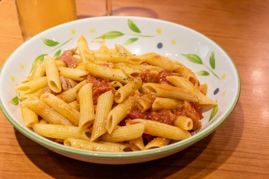 Pasta alfredo penne with tomato based sauce in plate