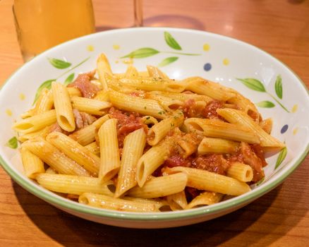 Pasta alfredo penne with tomato based sauce in plate