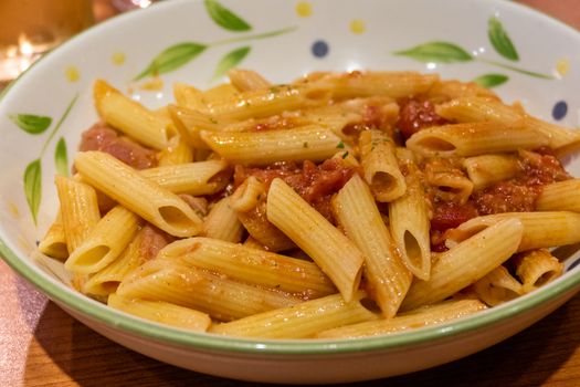 Pasta alfredo penne with tomato based sauce in plate