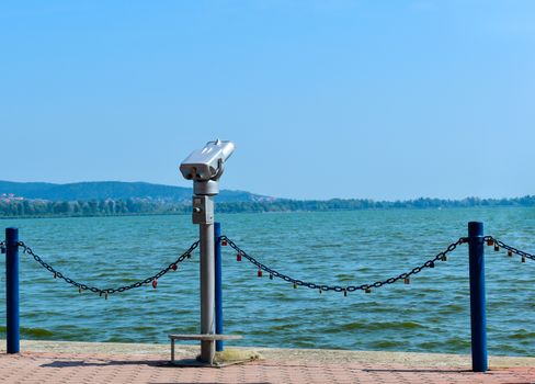 Binocular for viewing landscape in Keszthely. Love padlocks hang on the chains, in the background is Lake Balaton, the largest lake in Hungary.