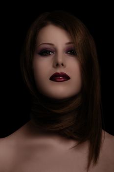 Low key sensual, make up, and beauty portrait of a woman with her hair around her neck on black background.