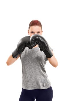 A portrait of a beautiful young girl with boxing gloves in a blocking stance, isolated on white background.