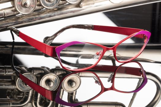 Fashinable glasses and trumpet on a studio galss background