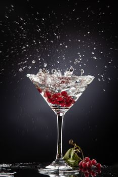 Bunch of red currant falling into the glass of water