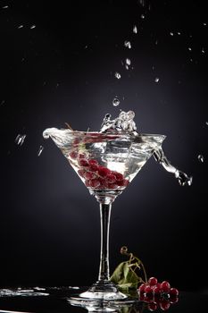 Bunch of red currant falling into the glass of water