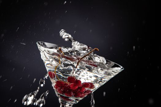 Bunch of red currant falling into the glass of water