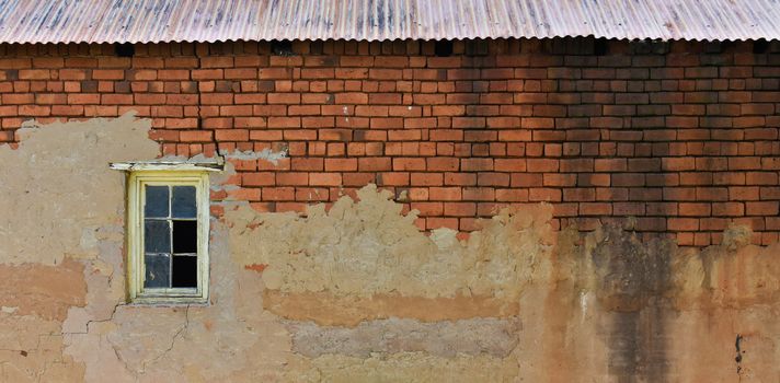 An old red clay brick warehouse wall with roof and window frame, Limpopo, South Africa